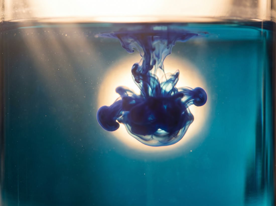 Tinte im Wasser, von hinten hell durchleuchtet und dadurch sichtbar
